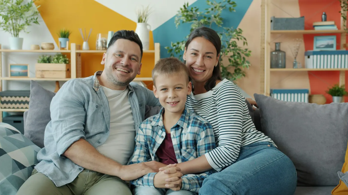 Smiling family of three sitting together on a couch