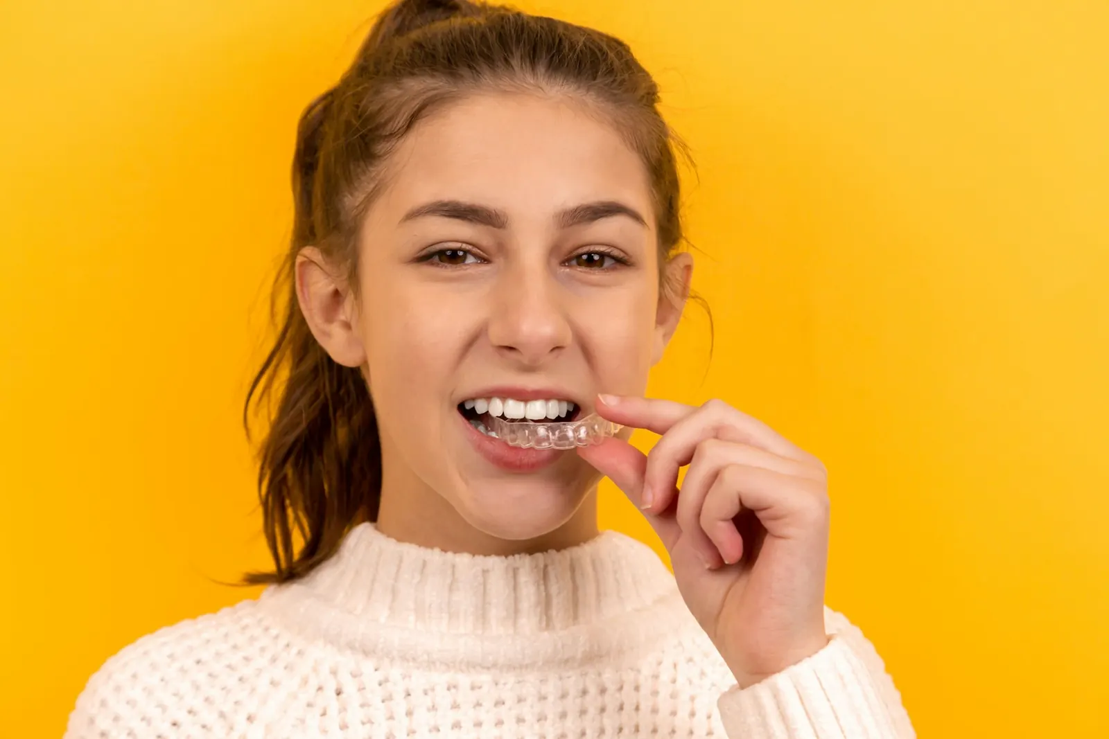 Smiling young woman holding a clear aligner