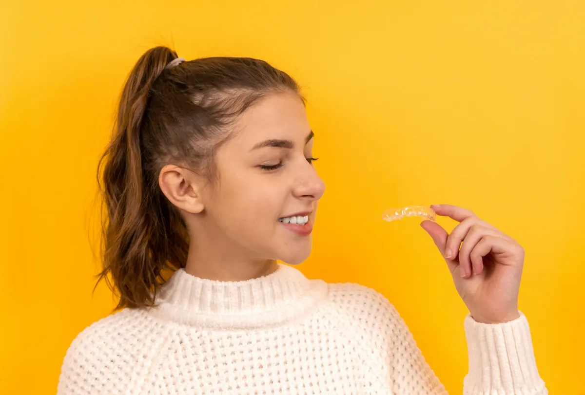 Teen holding her clear aligner